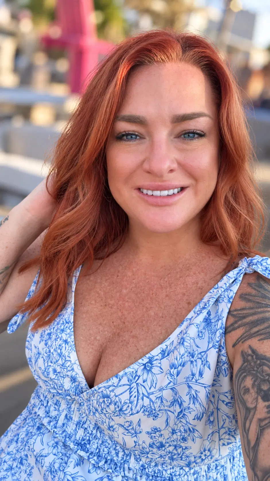 Amy, owner of Golden Hour Hair & Beauty Co., smiling in a blue-and-white floral dress