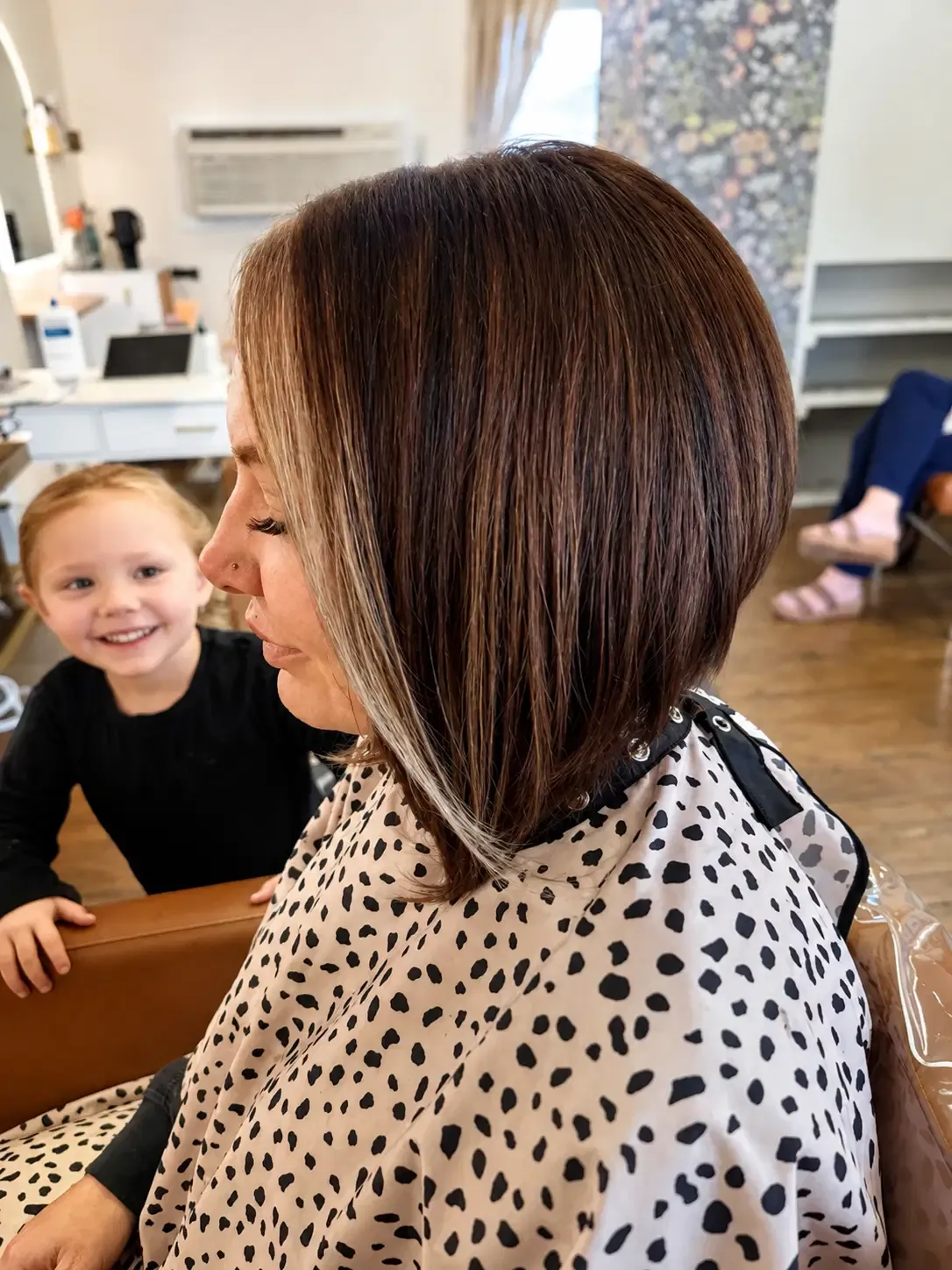 Client with a fresh shoulder-length brown bob and blonde face-framing pieces in the salon